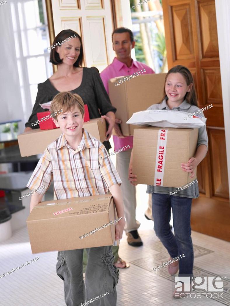 Stock Photo: Couple with young boy and girl carrying boxes into home.