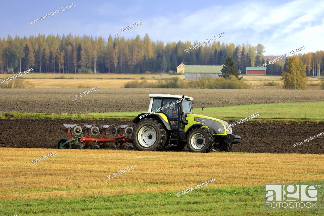 Stock Photo: Farmer plows field with green Valtra tractor and plough on a sunny autumn morning in South of Finland. Jokioinen, Finland. October 2, 2020.