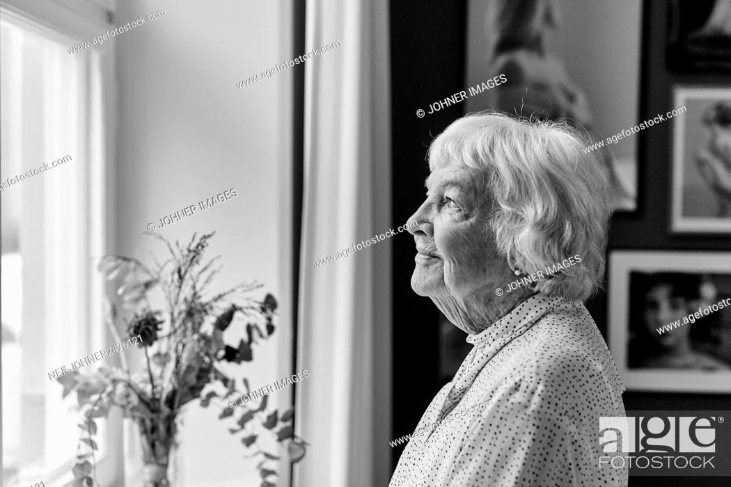 Stock Photo: Senior woman looking through window.