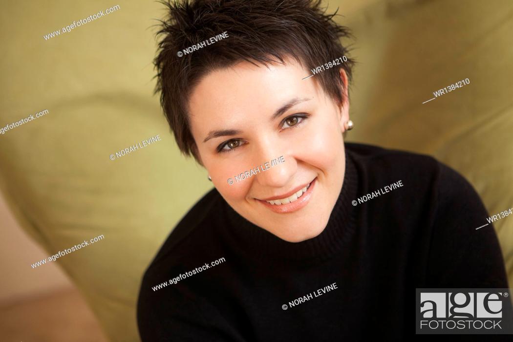 Stock Photo: A woman with short spiky brown hair, wearing a black turtleneck sweater. Smiling and looking up.