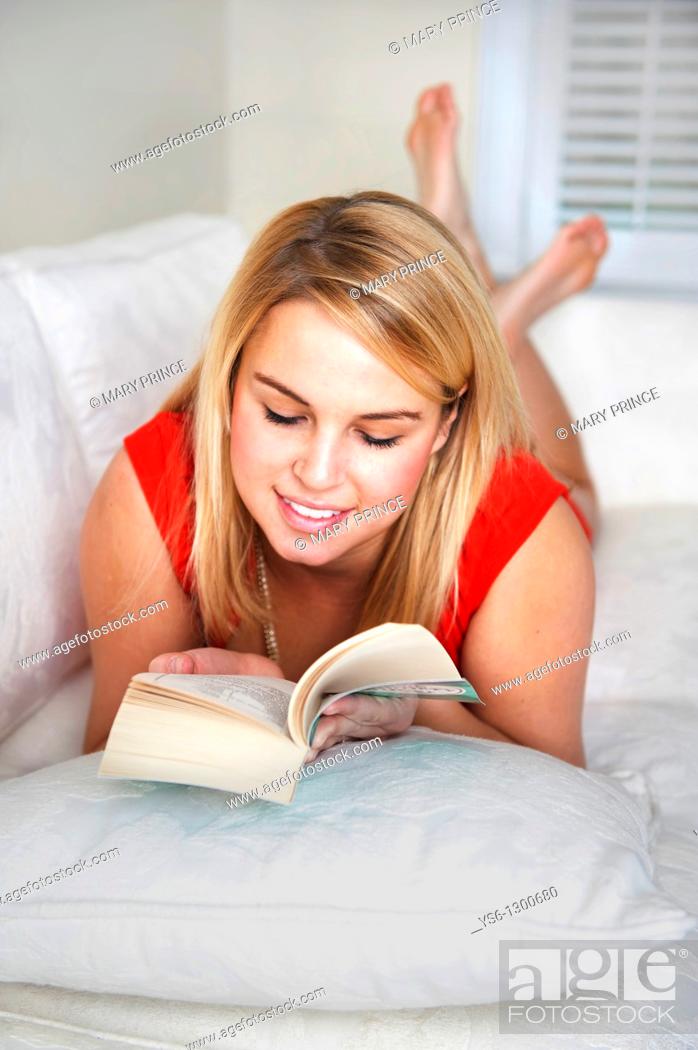 Photo de stock: Young blonde woman reading on couch.