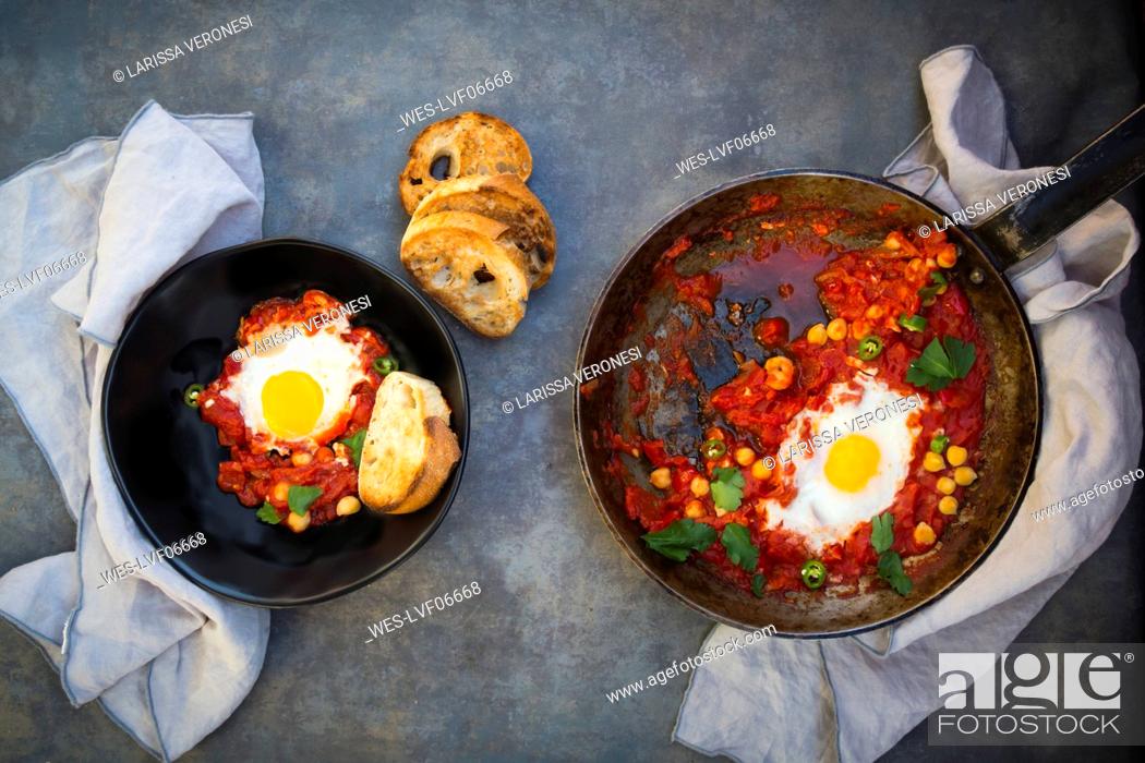 Stock Photo: Shakshouka with chick peas in pan and slices of roasted baguette.