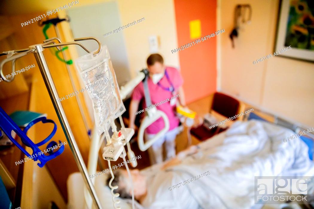 Stock Photo: PRODUCTION - 07 May 2021, Berlin: An infusion bag hangs above a patient bed in the visceral surgery ward of Havelhöhe Hospital.