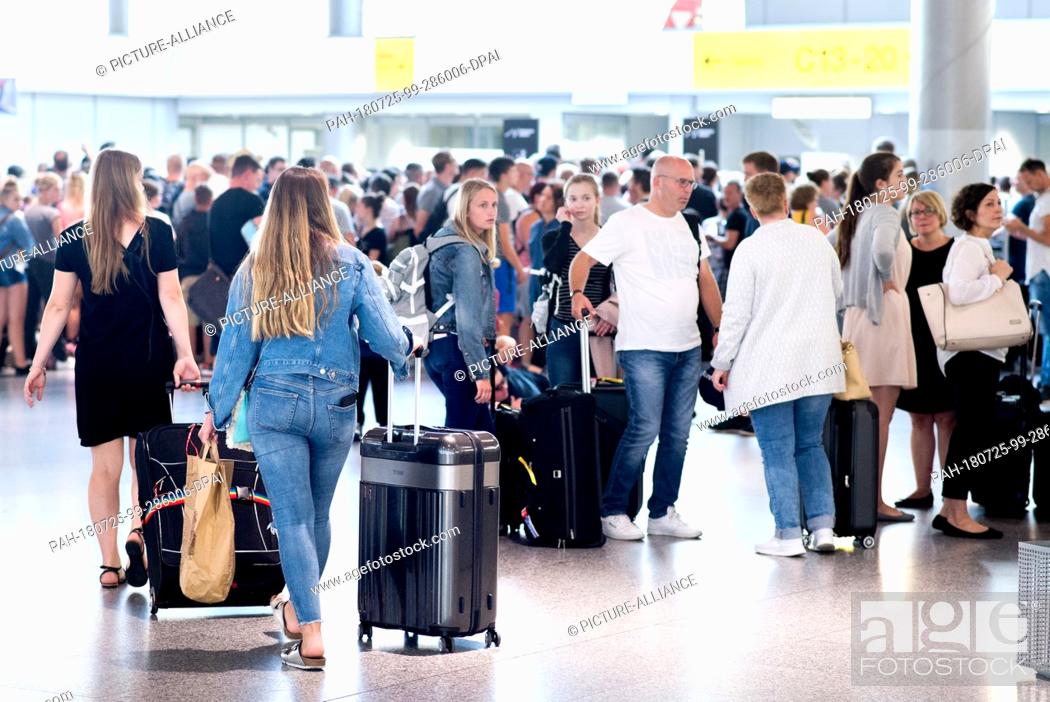 Stock Photo: 25 July 2018, Langenhagen, Germany: Passengers are standing with their luggage in front of a check-in counter in the departure hall of Hanover Airport.