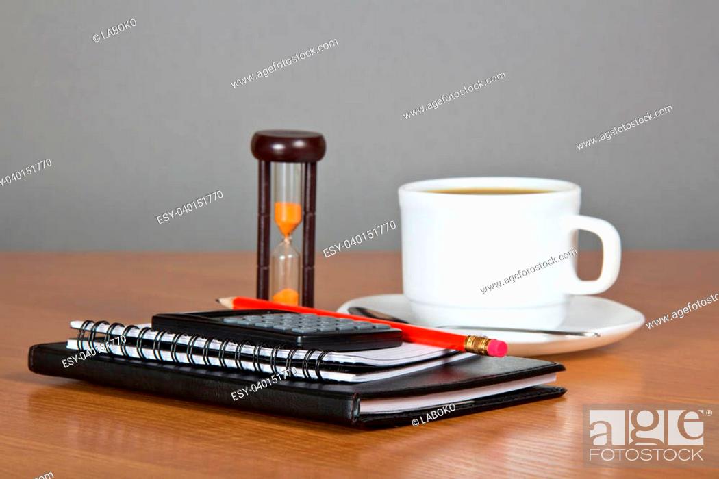 Stock Photo: Notepad a pencil the calculator, cup of coffee, saucer, spoon and hourglasses, on a gray background.