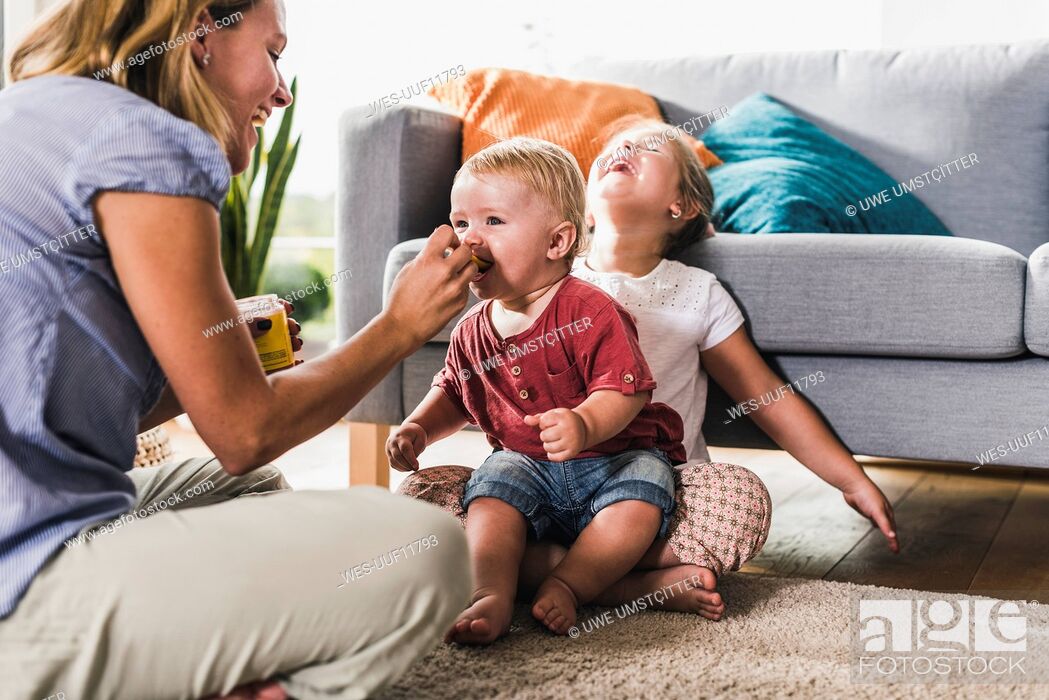 Stock Photo: Mother feeding kids in living room.
