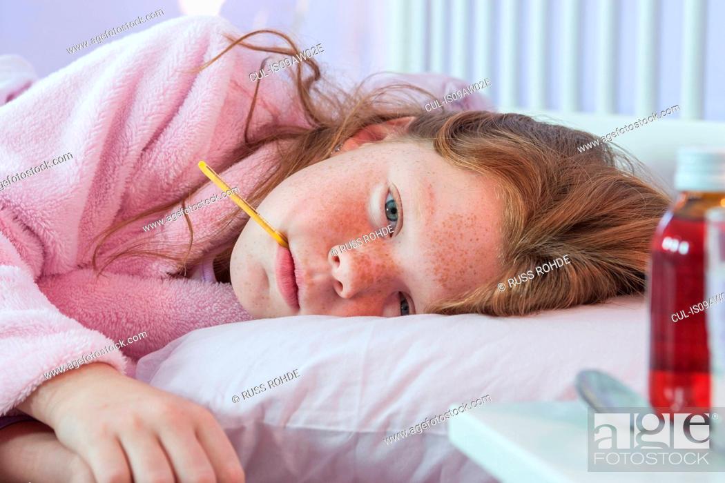Stock Photo: Close up of girl lying in bed with thermometer in her mouth.
