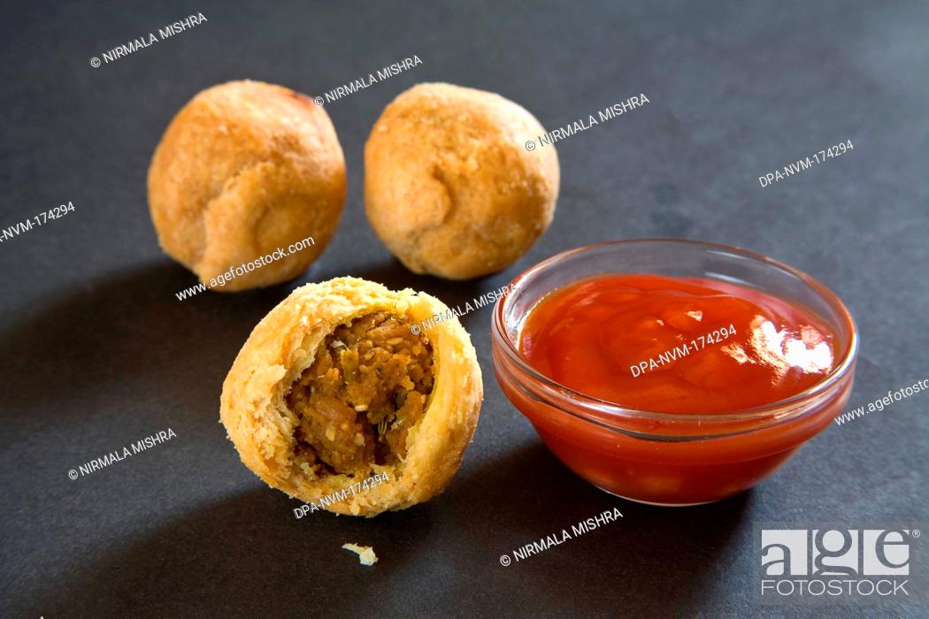 Stock Photo: Indian fast food fried kachori with tomato ketchup on black background 15-April-2010.