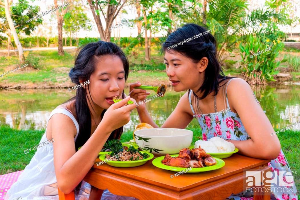 Stock Photo: Asian Thai girls picnic together beside swamp.