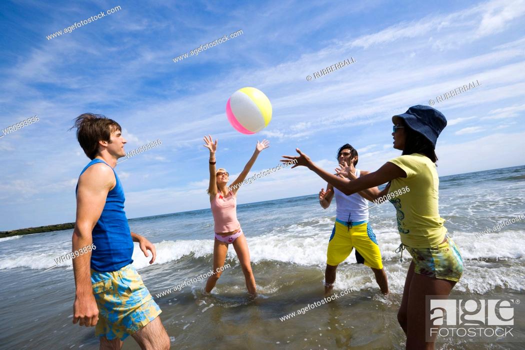 Stock Photo: Four young people playing with a beach ball.