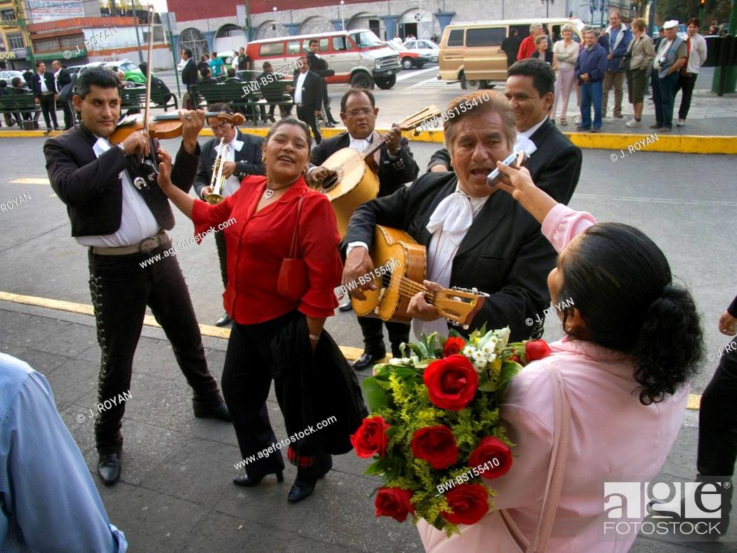 Stock Photo: A woman asks a musician to sing on her cell phone during a 'serenata'. Mariachis in Plaza Garibaldi, Mexico, Mexico City.