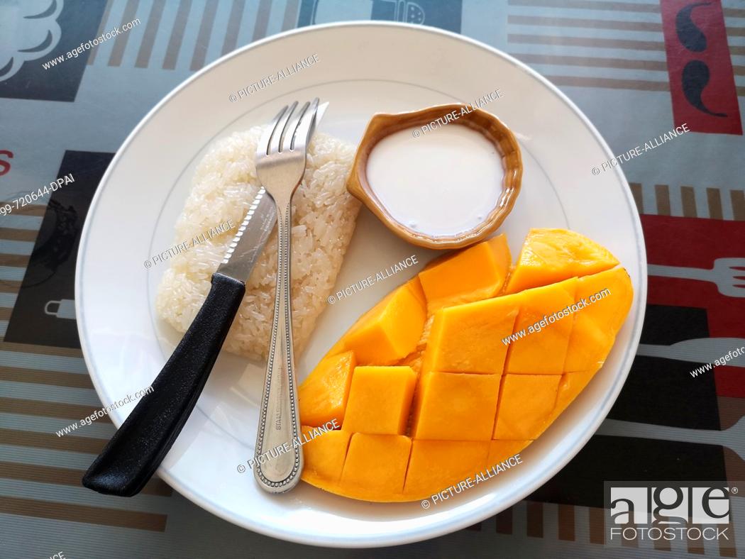 Stock Photo: 14 March 2019, Thailand, Karon Beach: Sticky Riche with mango, glutinous rice with mango and coconut sauce, a typical Thai specialty, on a plate.