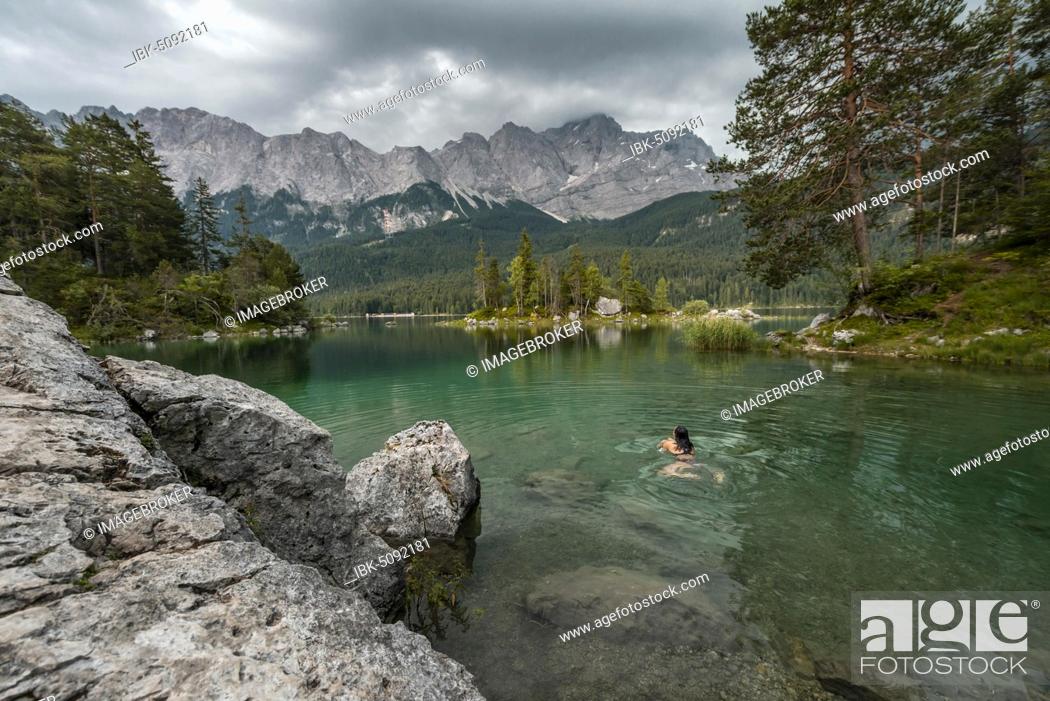 Stock Photo: Woman swimming in the lake, view of Eibsee lake in front of Zugspitze massif with Zugspitze, cloudy, Wetterstein range, near Grainau, Upper Bavaria, Bavaria.