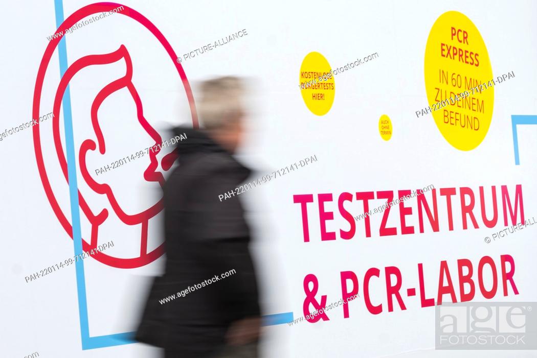 Stock Photo: 14 January 2022, Lower Saxony, Hanover: A man walks past a test center for the Corona virus (long exposure shot). The number of new Corona infections reported.