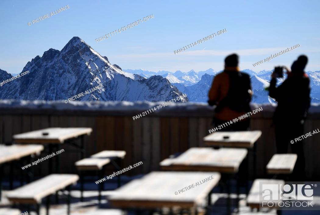 Stock Photo: 07 November 2021, Bavaria, Grainau: Two visitors photograph the panorama of the Wetterstein Mountains from the Zugspitze.