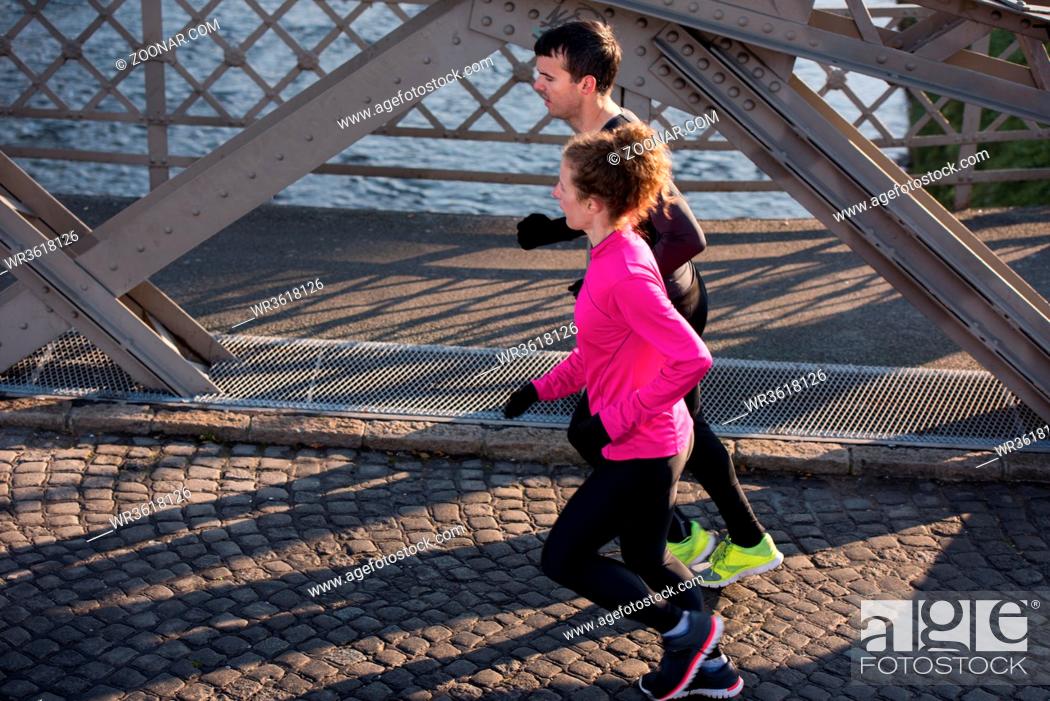 Stock Photo: healthy young couple jogging in the city at early morning with sunrise in background.