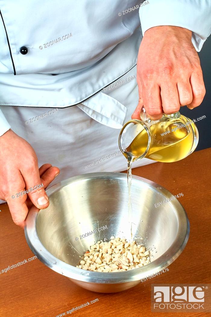 Stock Photo: The cook pours olive oil into a bowl full of recipes for eating jelly with chicken.
