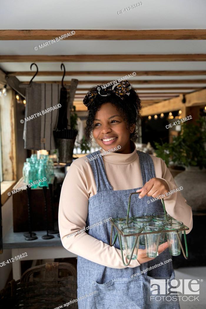 Stock Photo: Portrait happy female shop owner holding glass plant holder.