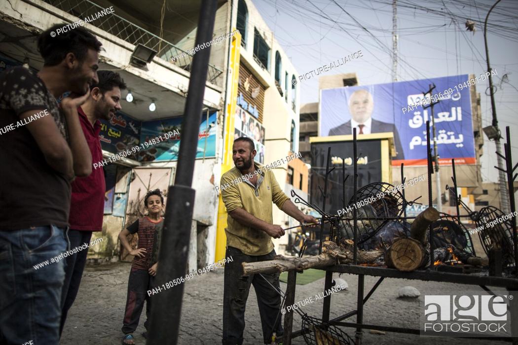 Stock Photo: A picture made available on 07 May 2018 shows a man selling grilled fish backdropped by a campaign poster of Iraqi Prime Minister Haider al-Abadi in Baghdad.
