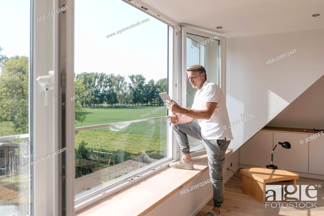 Stock Photo: Mature man using tablet at the window in empty room.