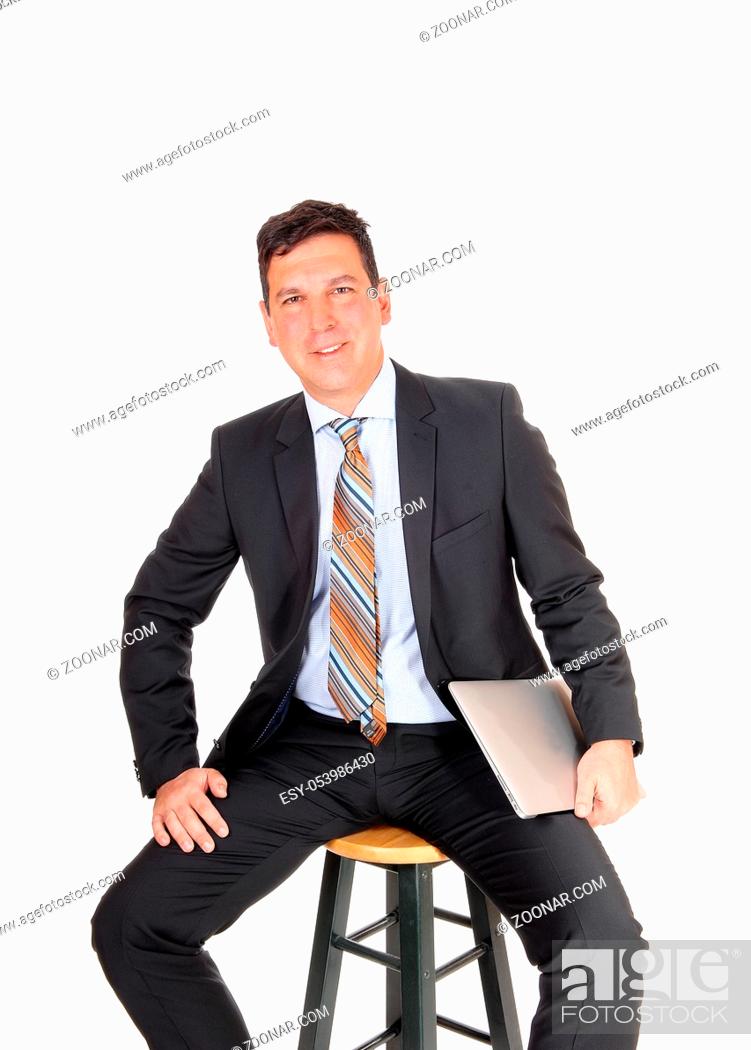 Stock Photo: A handsome middle age business man sitting on a chair and smiling holding his laptop, isolated for white background.