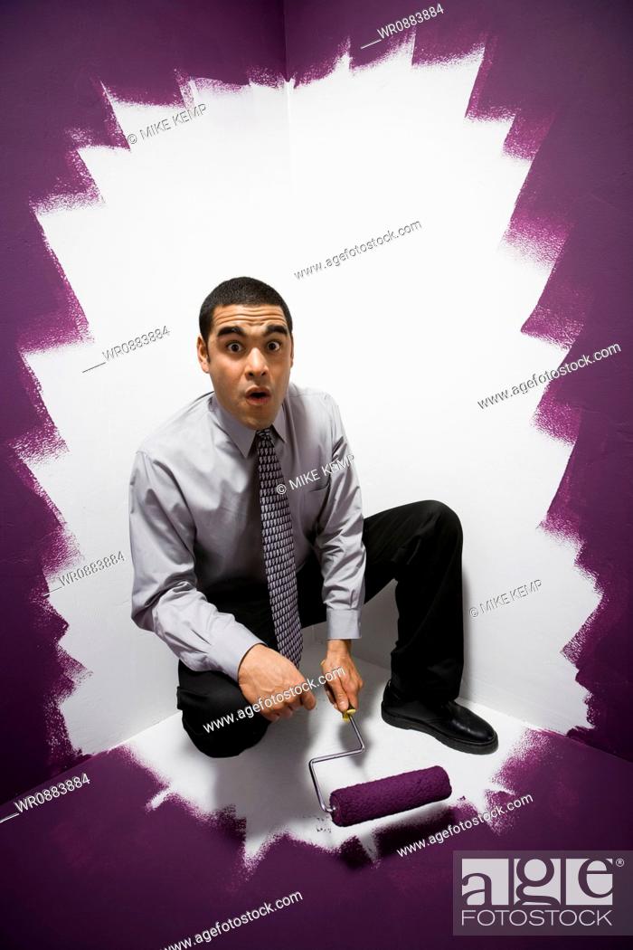 Stock Photo: Portrait of a businessman painting himself into a corner.