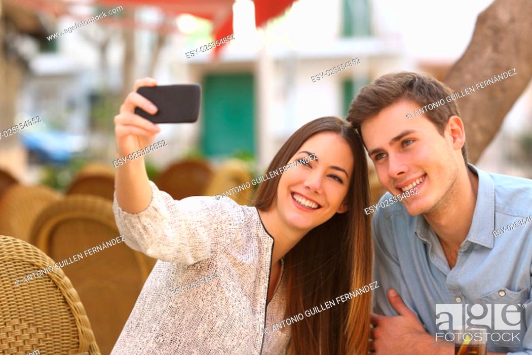 Stock Photo: Happy couple taking a selfie photo with a smart phone in a restaurant terrace.