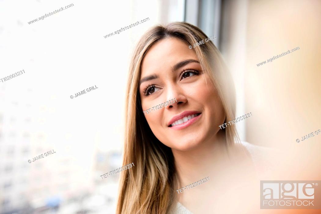 Stock Photo: Portrait of young woman looking through window.