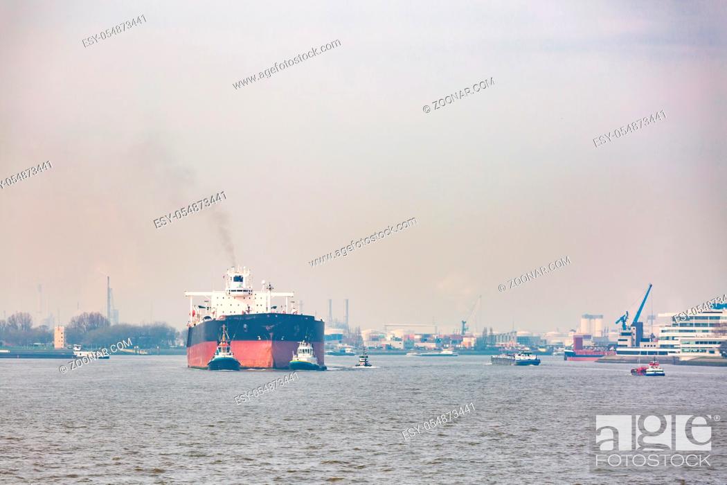Stock Photo: Big Cargo Containers Boat with Goods cargo Stack at the Pier docks port waiting for international sea freight transportation in Rotterdam Port of Netherlands.