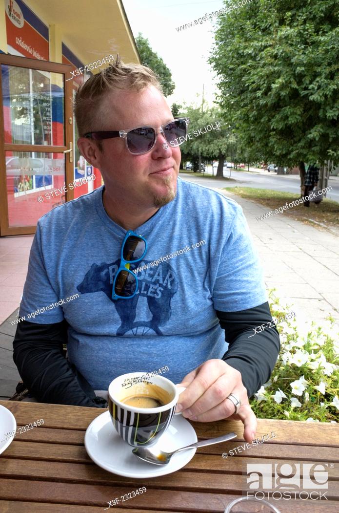 Stock Photo: American man living in Poland enjoying his espresso at a sidewalk cafe. Rawa Mazowiecka Central Poland.