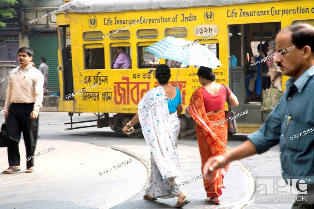 Stock Photo: Two sari clad women passing near at yellow tram Indian street scene in Calcutta now Kolkata ; West Bengal ; India.
