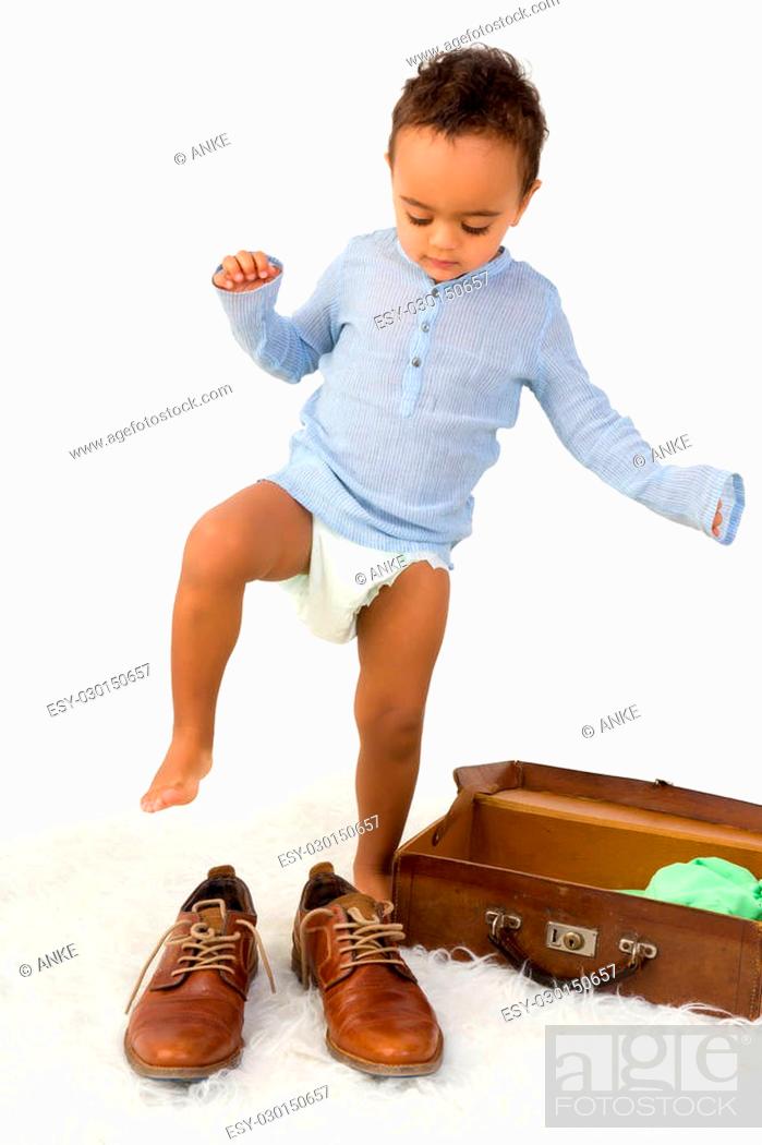 Stock Photo: Playful African toddler boy having fun with Dad's shoes.