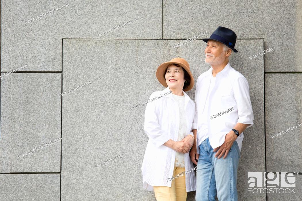 Stock Photo: Senior couple standing against wall.