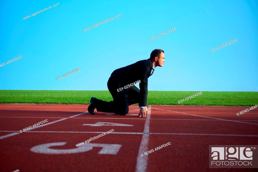 Stock Photo: business man in start position ready to run and sprint on athletics racing track.