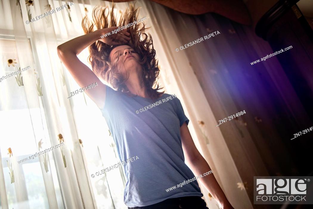 Stock Photo: A young woman waving her hair indoors.
