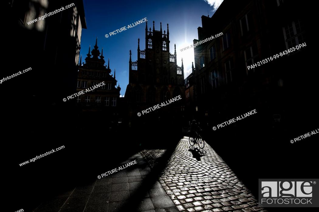 Stock Photo: ATTENTION: EMBARGOED FOR PUBLICATION UNTIL 16 MARCH 12:00 GMT! - 16 March 2021, North Rhine-Westphalia, Münster: A man rides his bicycle on Prinzipalmarkt and.
