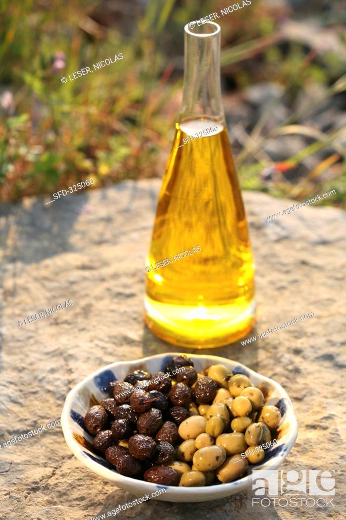 Stock Photo: Olive oil in carafe, two types of olives in bowl out of doors.