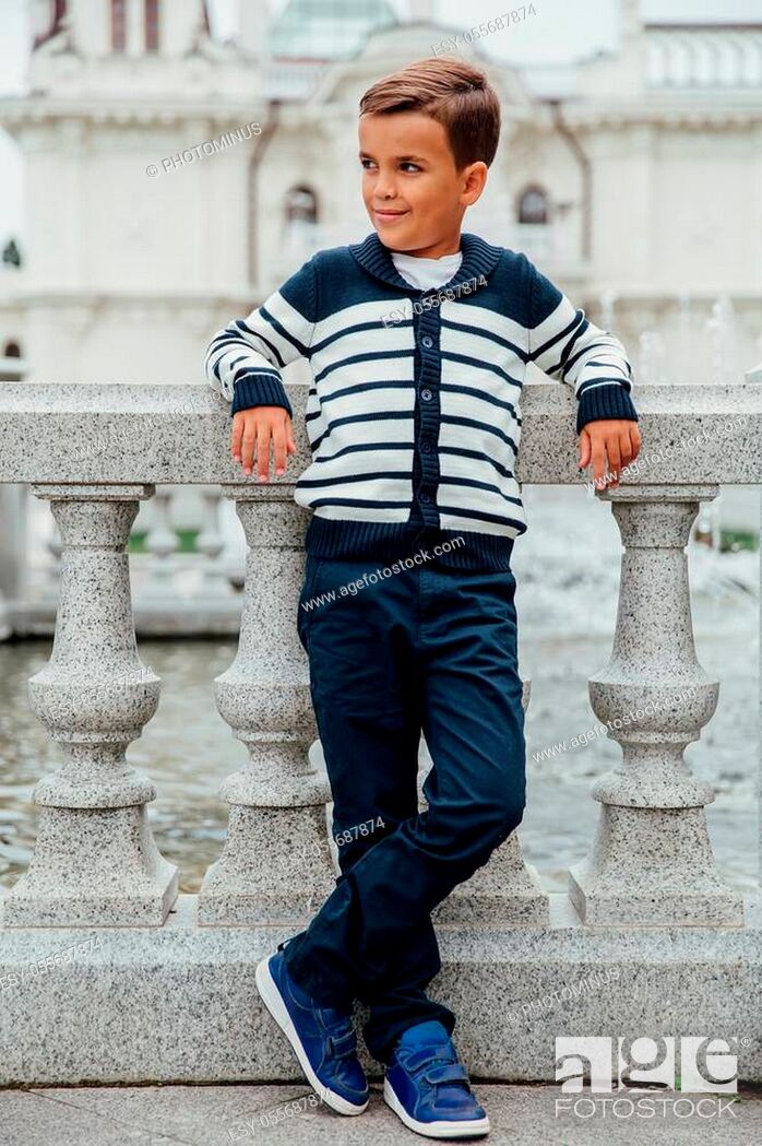 Stock Photo: Stylish rich little boy in fashionable clothes. Leaned on Granite-stone handrails. stylish, handsome posing outside in the city park.