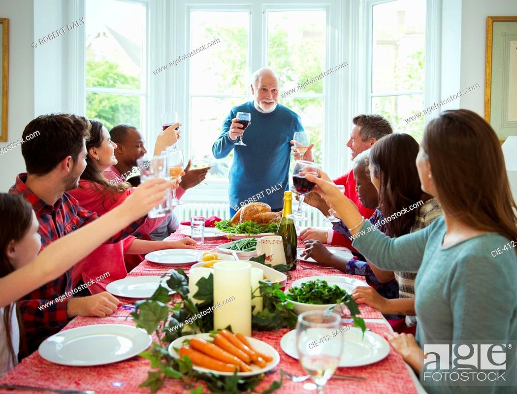 Stock Photo: Grandfather making toast with wine at Christmas dinner table.