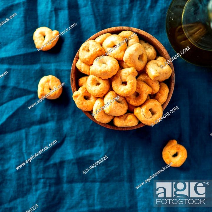Stock Photo: Traditional italian snack taralli or tarallini in wooden bowl over dark blue linen napkin background. Rustic shot of taralli appetizer with copy space.