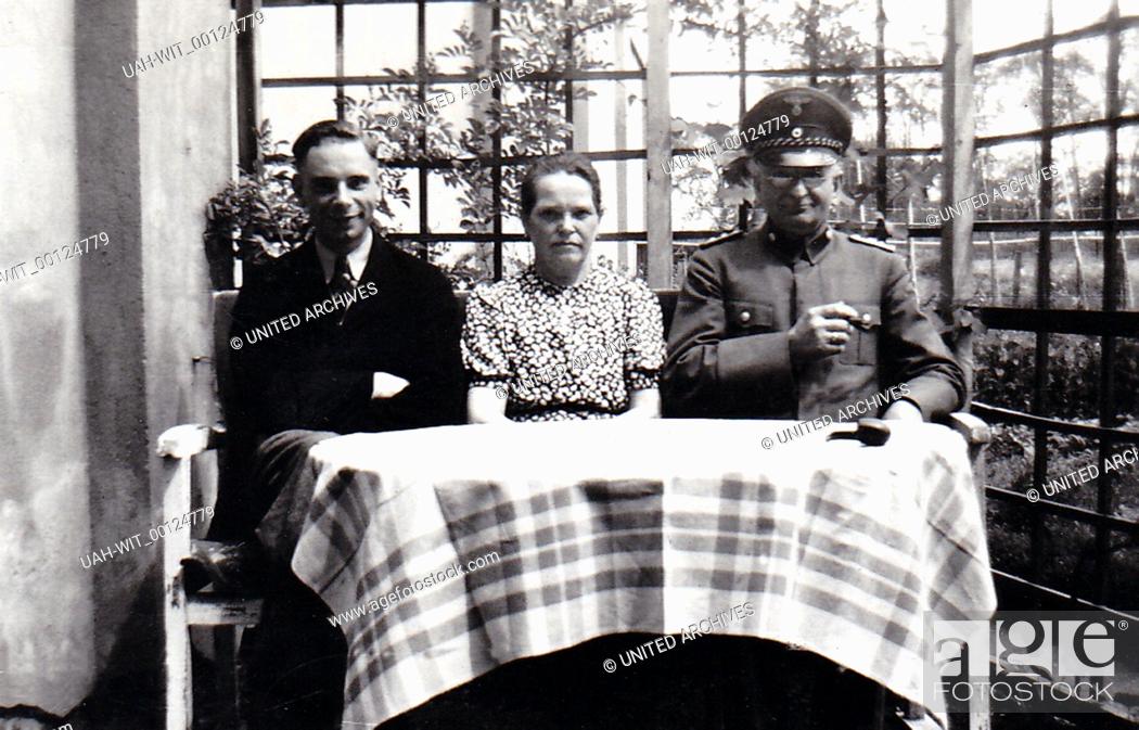 Stock Photo: Ein junges Paar sitzt mit einem älteren Uniformierten am Gartentisch., Sammlung Wittmann.