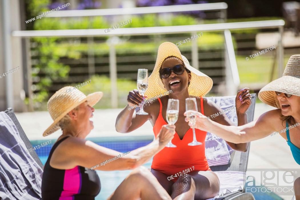 Stock Photo: Happy senior women friends drinking champagne at sunny summer poolside.