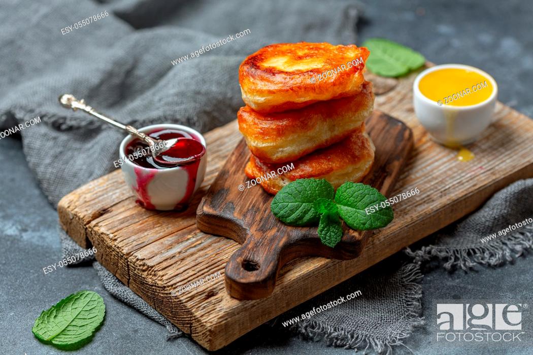 Stock Photo: Homemade pancakes with berry sauce are served on a wooden serving board with a sprig of mint, selective focus.