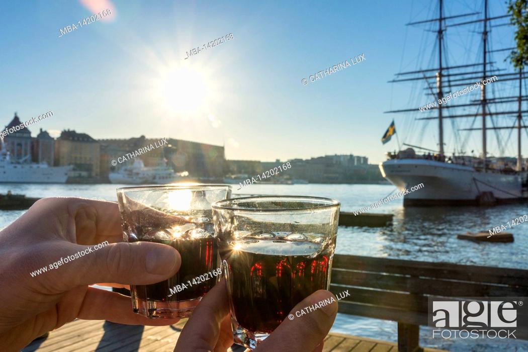 Stock Photo: Sweden, Stockholm, Skeppsholmen, picnic, two hands holding two glasses, back light.