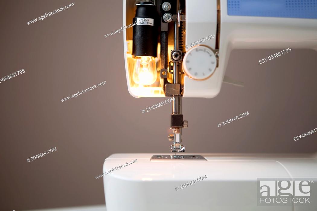Stock Photo: Sewing machine with open lamp on empty gray background.
