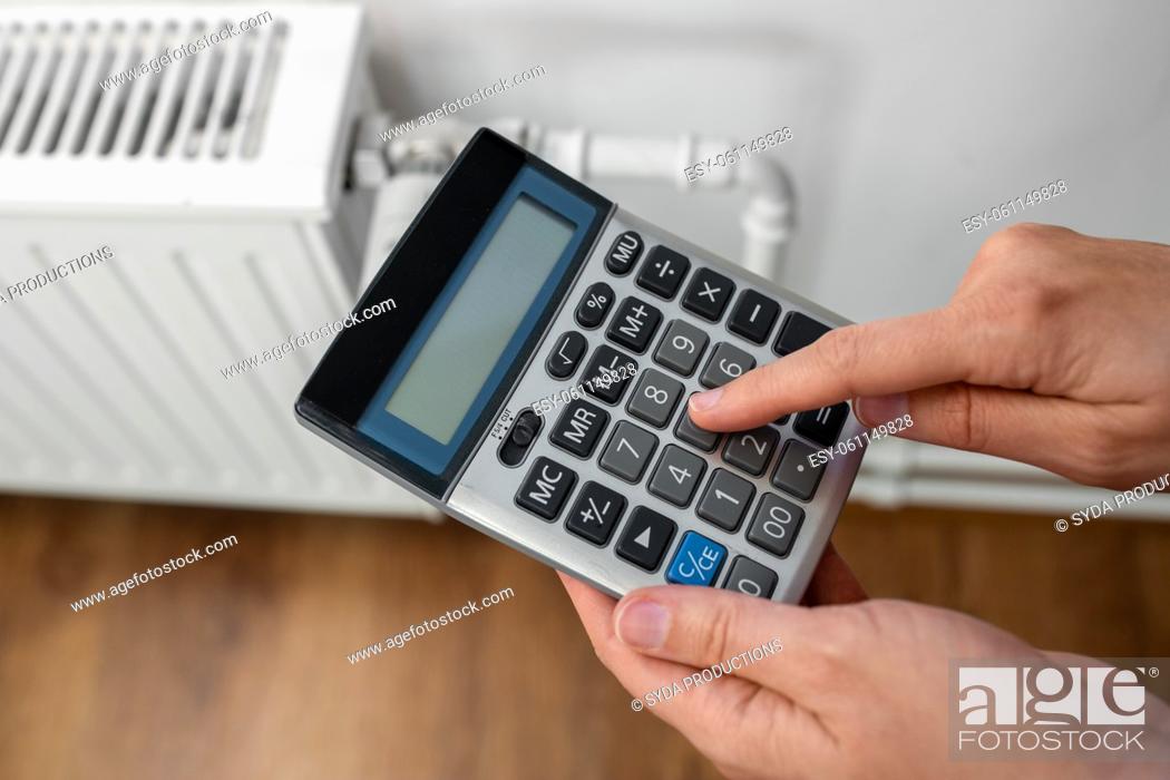 Stock Photo: close up of hand with calculator and home radiator.