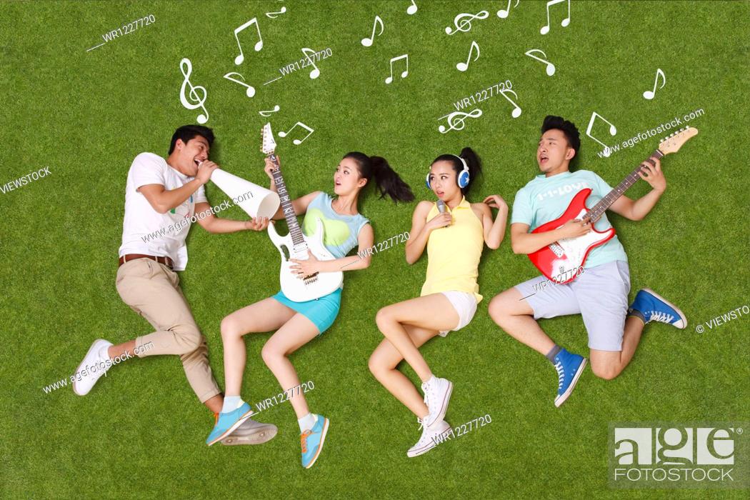 Stock Photo: Young people on grass playing musical instruments.