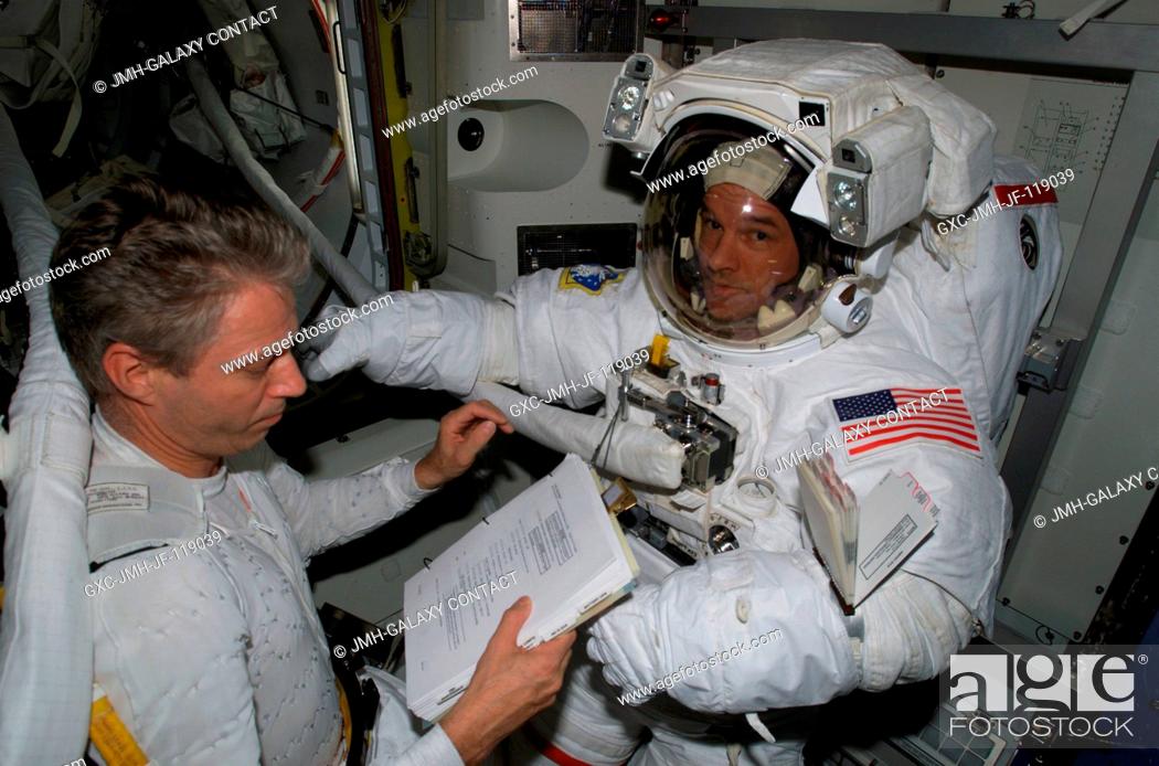 Stock Photo: European Space Agency (ESA) astronaut Thomas Reiter (left), Expedition 13 flight engineer, looks over a procedures checklist as he assists astronaut Jeffrey N.