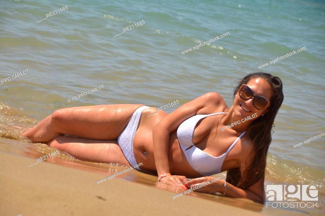 Photo de stock: Girl posing in bikini lying on the seashore in summer.