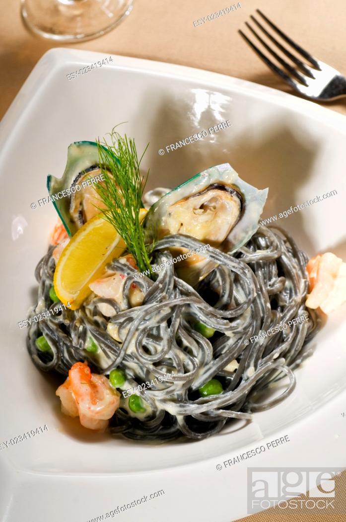 Imagen: fresh seafood black squid ink coulored spaghetti pasta tipycal italian food.